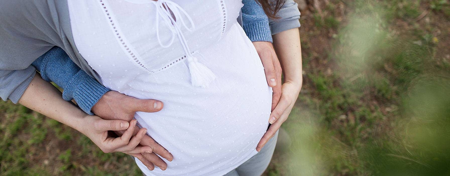 Hände auf dem Bauch einer schwangeren Frau