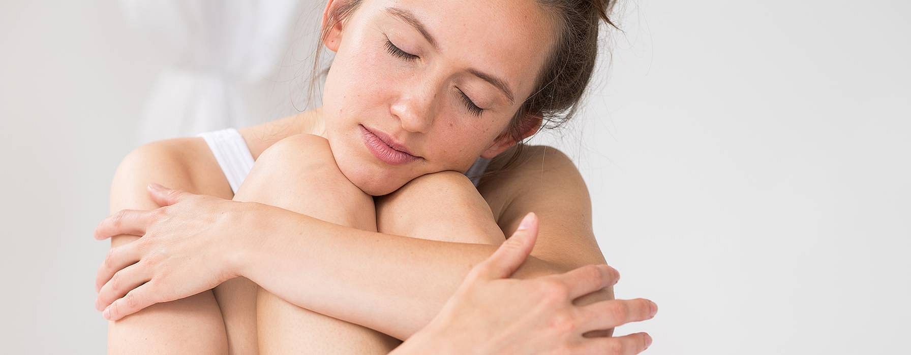 Frau haelt liebevoll ihre Beine umfangen