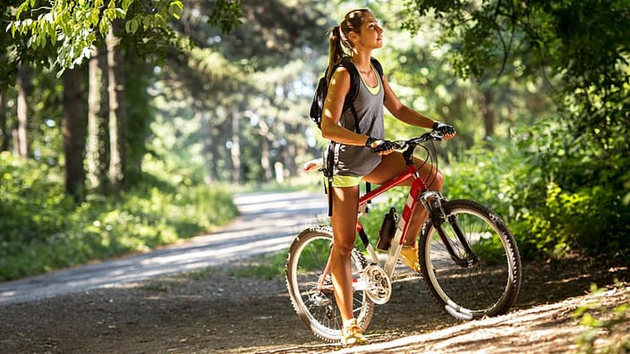 Frau mit Fahrrad im Wald