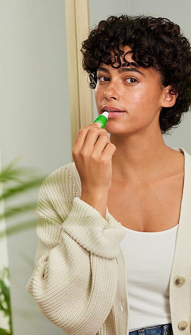 Young woman applying skin food lip Butter