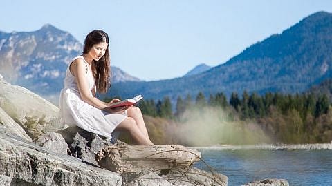 Frau sitzt am Fluss