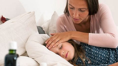 Mama legt die Hand auf die Stirn vom schlafenden Mädchen
