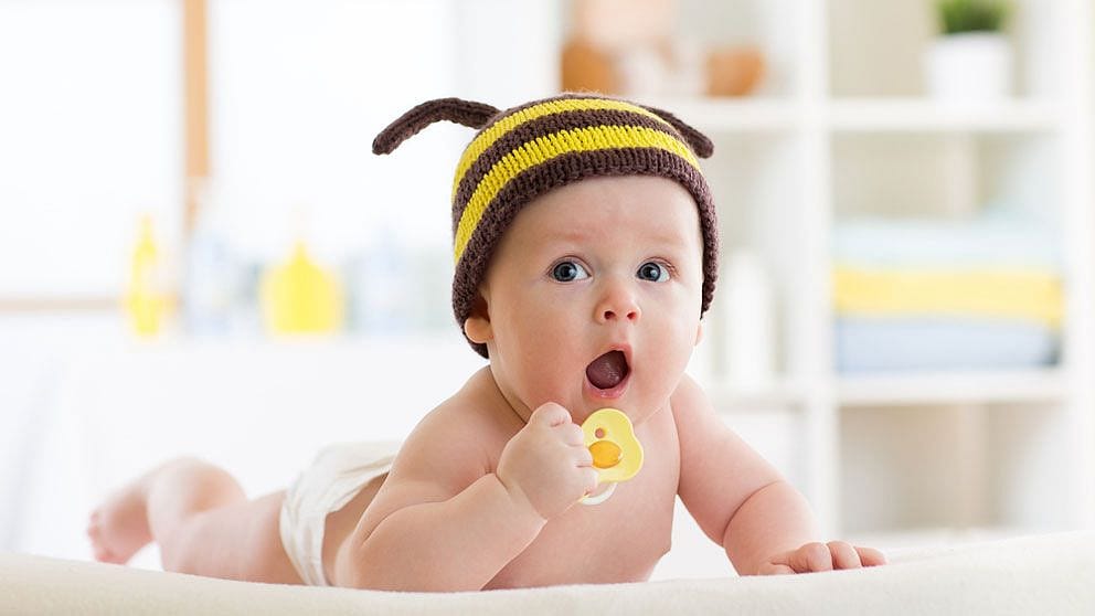 Baby liegt auf dem Bauch und hebt den Kopf