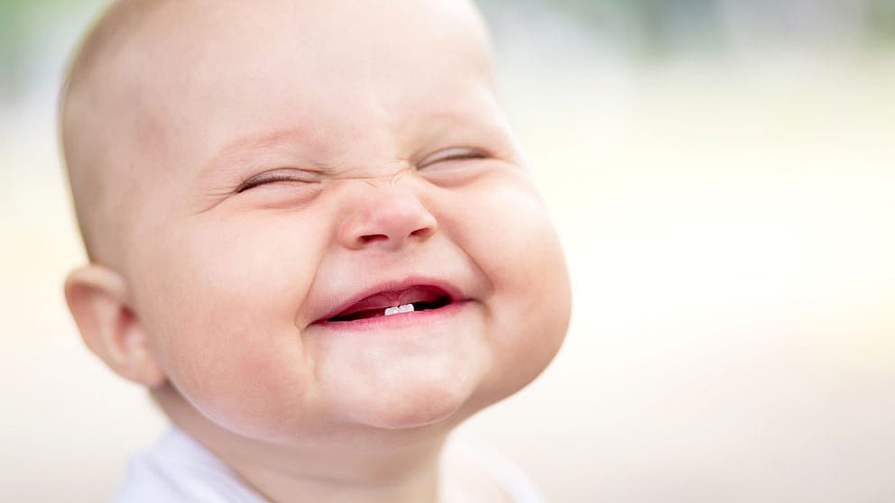 Baby lacht und zeigt erste Zähne