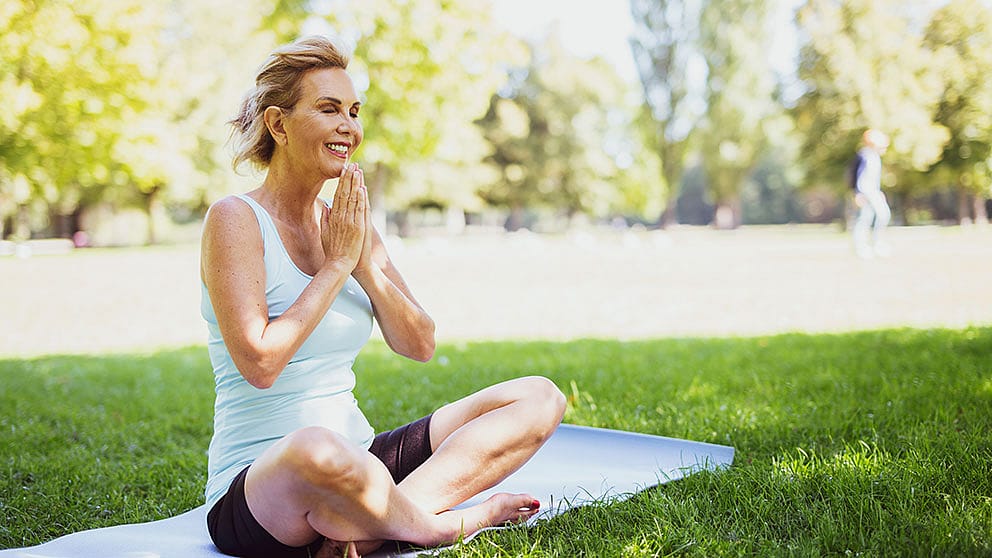 Aeltere Frau macht Yoga im Park