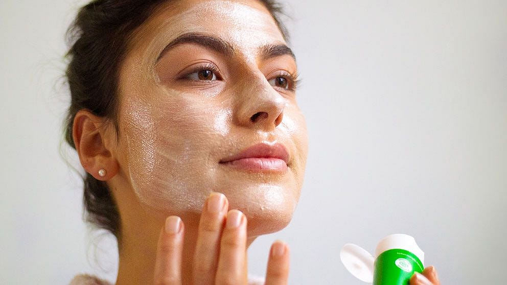 junge frau trägt weleda skin food im gesicht auf