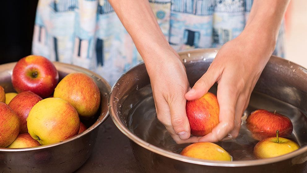 Frauenhaende waschen Obst in einer Schuessel