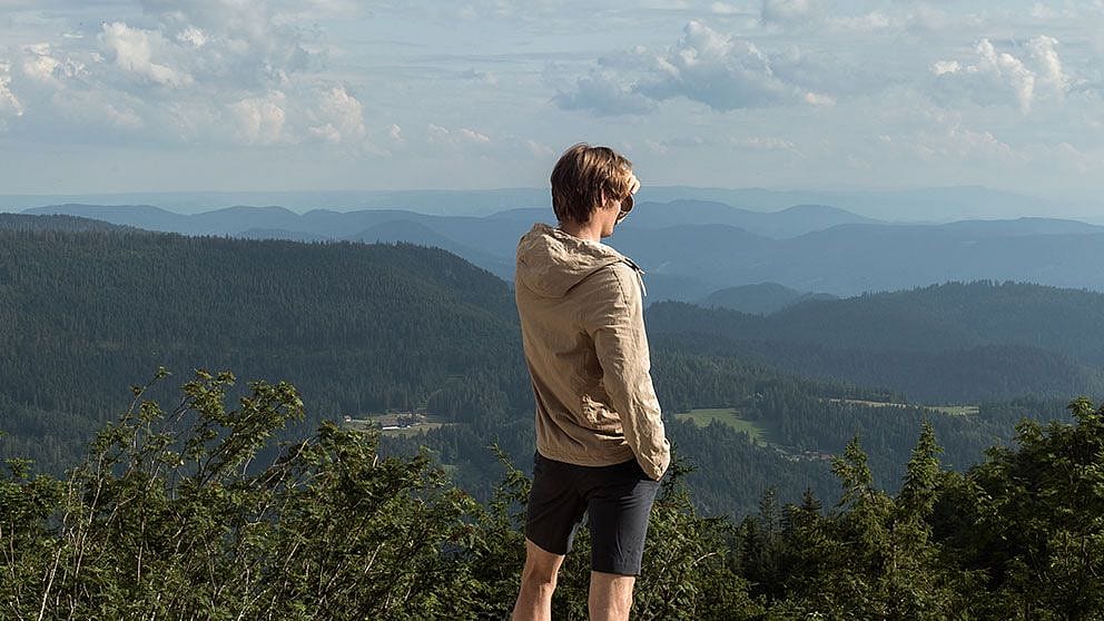 Mann steht auf einem Berg und blickt in die Ferne