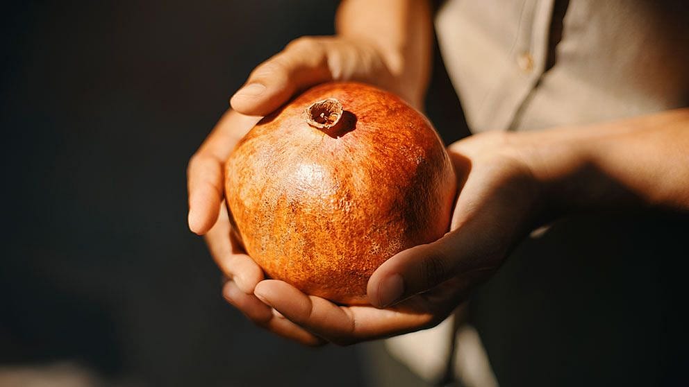 Frau hält Granatapfel in ihren Händen